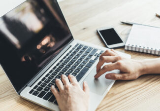 Mens hands on a laptop - smart phone and notepad